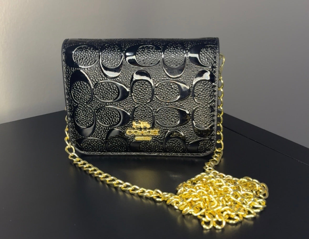 Coach-style mini crossbody bag features a bold black embossed signature